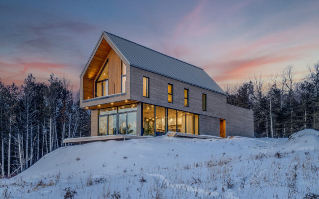 Résidence contemporaine nichée en pleine nature, où lignes épurées et matériaux nobles s’harmonisent au coucher de soleil hivernal.