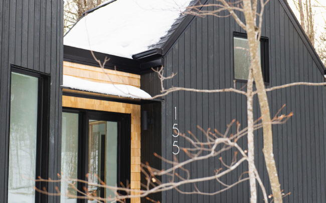 Détails raffinés et contraste élégant entre bois blond et façade noire : l’entrée de cette maison révèle tout son cachet scandinave.