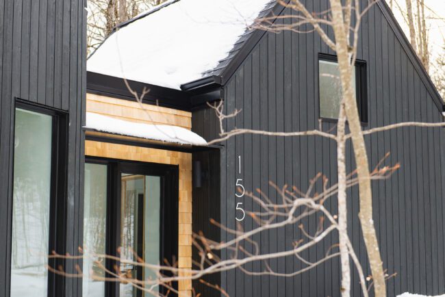 Détails raffinés et contraste élégant entre bois blond et façade noire : l’entrée de cette maison révèle tout son cachet scandinave.
